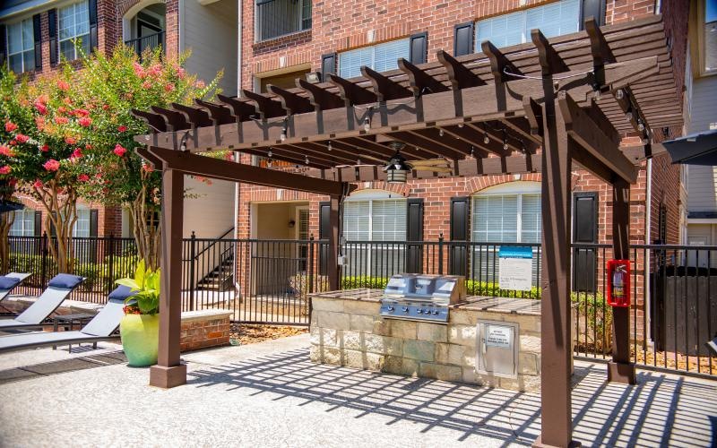 a pergola with a barbeque grill under it